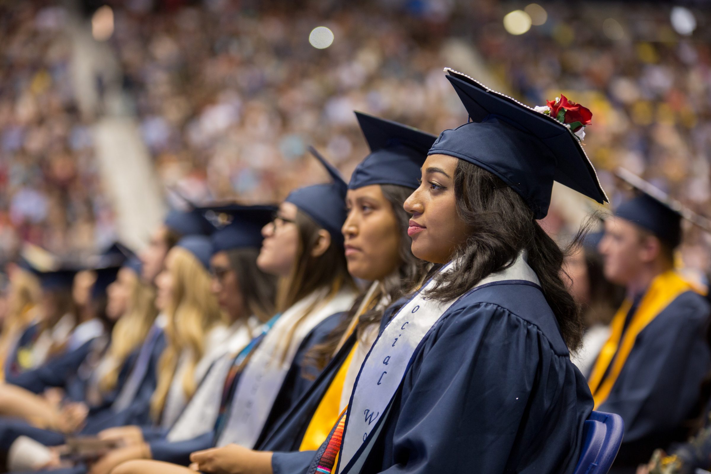 A row of students wearing caps and gowns at a Commencement ceremony.