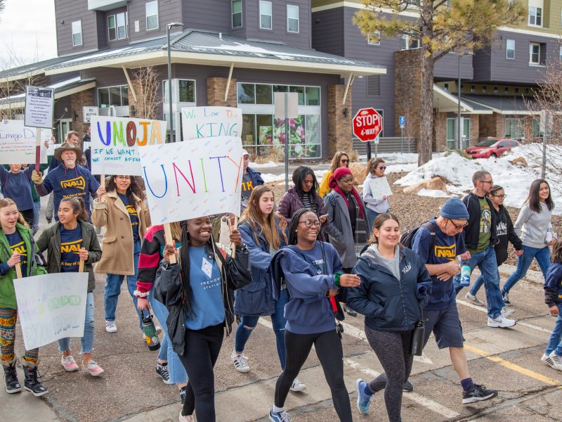 A crowd of students holding signs and marching for M L K Day.