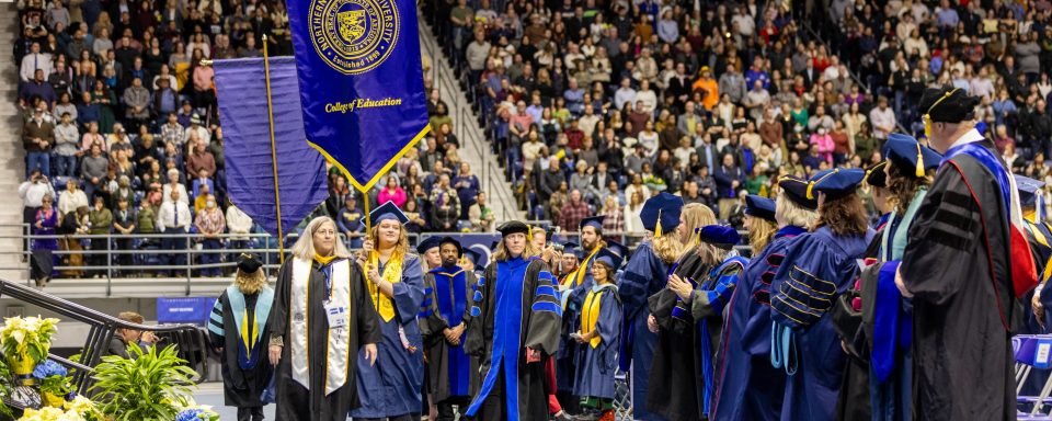 faculty procession at commencement, student holding college of education banner
