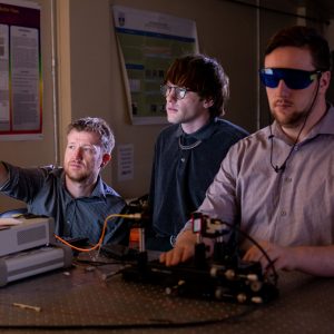 Professor Mann discusses experimental results with students in the lab