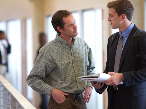 business student dressed in a suit is talking with an instructor in the NAU business building
