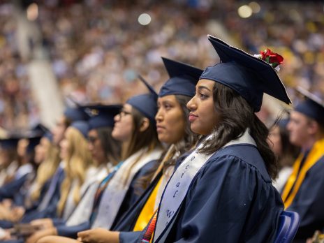 students wearing caps and gowns, seated, looking forward at graduation
