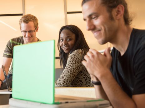 student smiling at another student on a laptop
