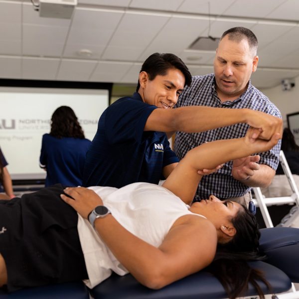 A athletic training student lifting up a patient's arm.