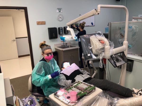 A dental hygienist cleaning a kids teeth.