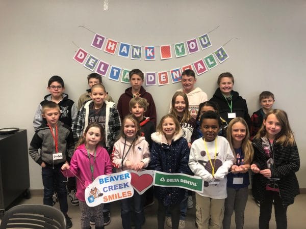 A group of kids smiling and holding a banner.