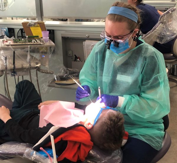 A dental hygienists cleaning a child's teeth.