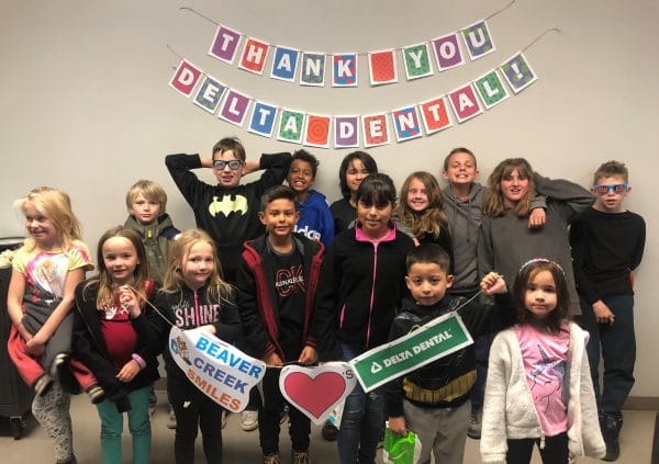 A group of kids smiling and holding a banner.