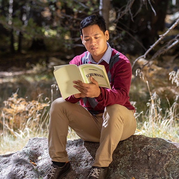 Ye Lynn Han sitting on a rock outdoors, reading