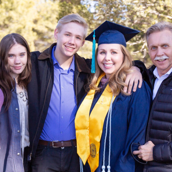 A young woman in graduation regalia surrounded by her family