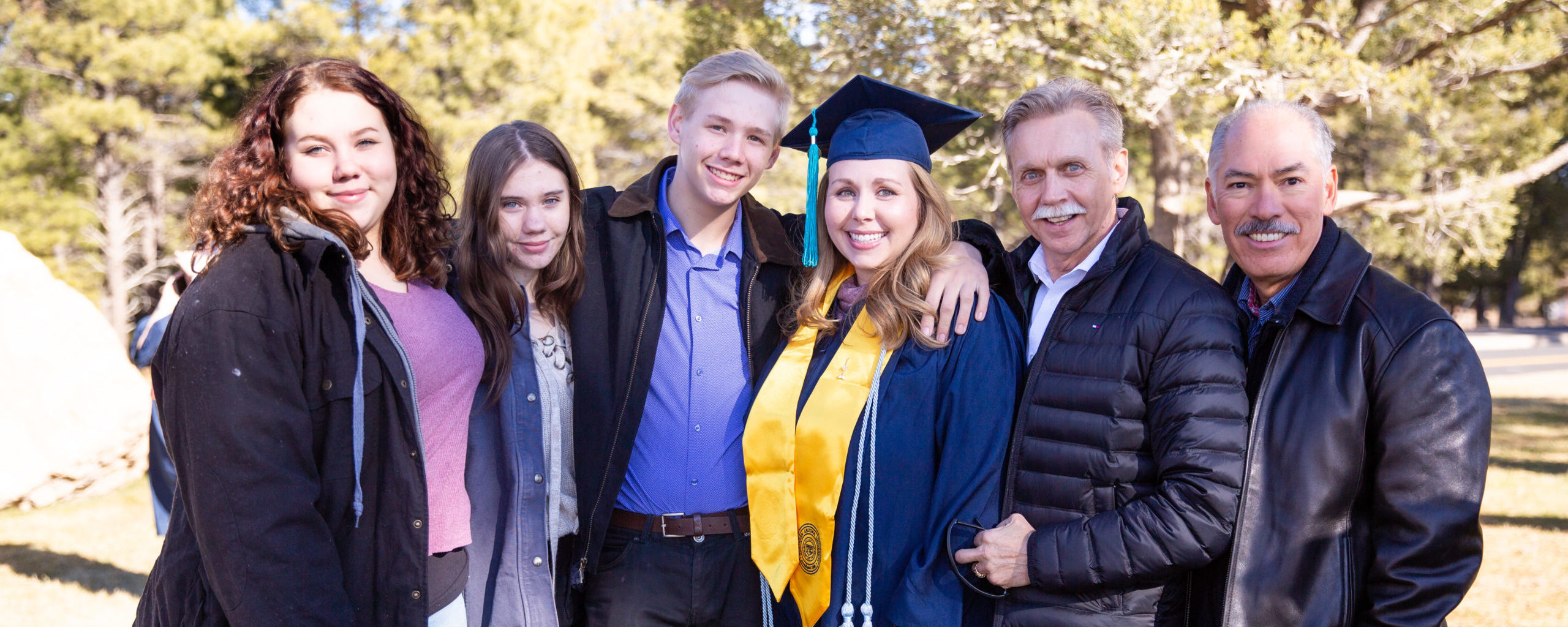 A young woman in graduation regalia surrounded by her family
