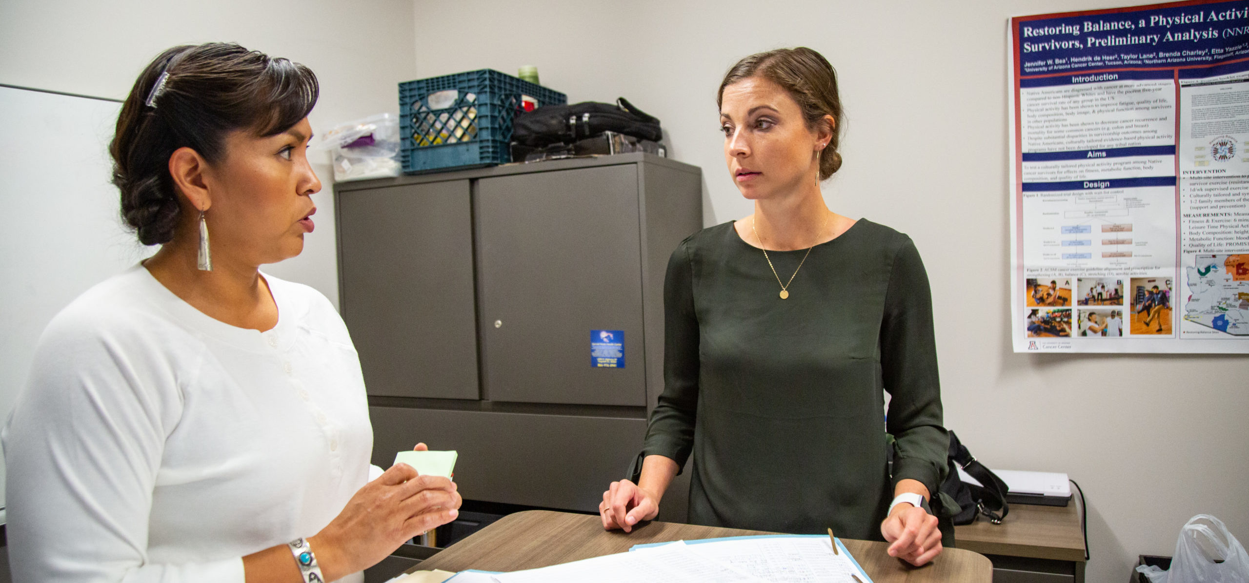 Taylor Lane speaks with another woman while consulting paperwork