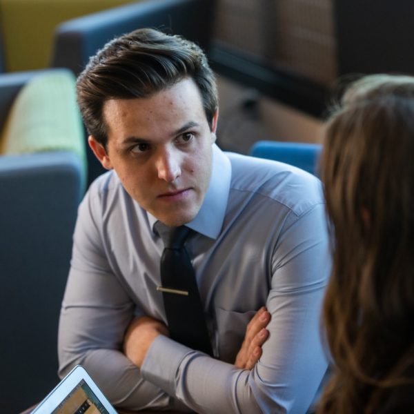 Anthony Mirabito, in a dress shirt and tie, in conversation with a woman