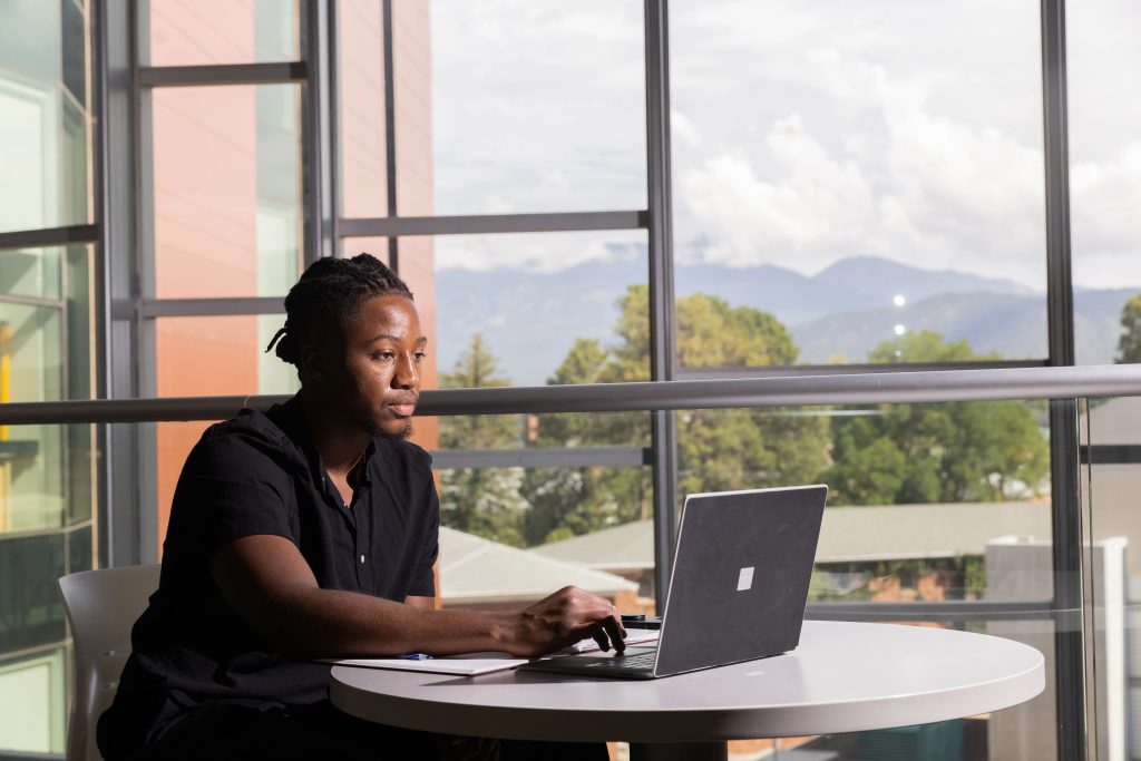 Zachariah Bess studying indoors with a view of the San Fracisco peaks in the background.