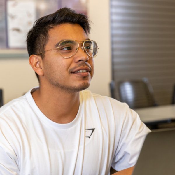 Gerardo Noriega in a classroom with a laptop and genetics textbook.