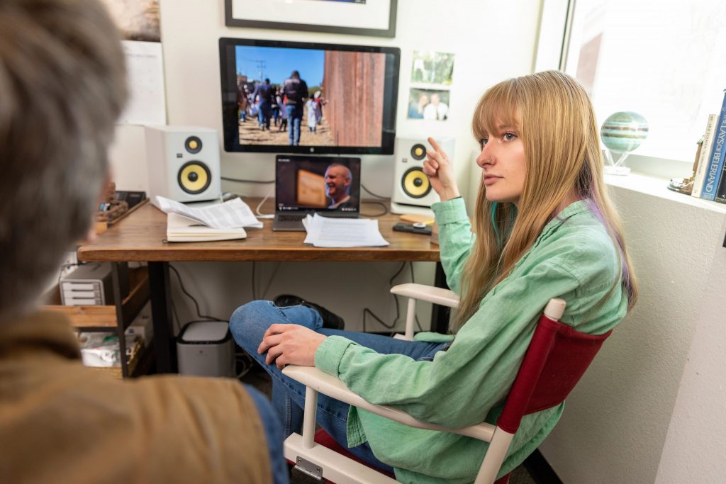 Mackenzie Baradic working on her documentary film while sitting at her desk and editing bay.