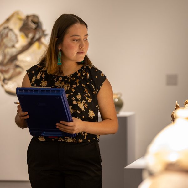 Autumn Begay carrying a clipboard in an art museum.