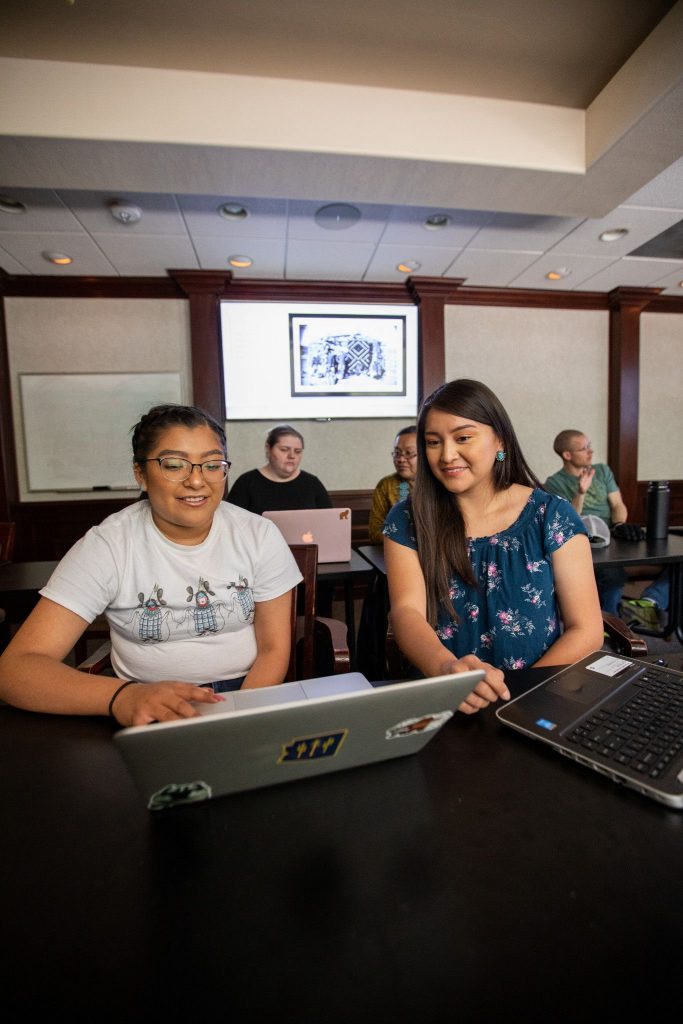 Students working on a laptop in an Applied Indigenous Studies classroom.