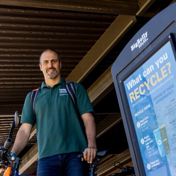 Avi Henn standing with e-bike next to recycling container.