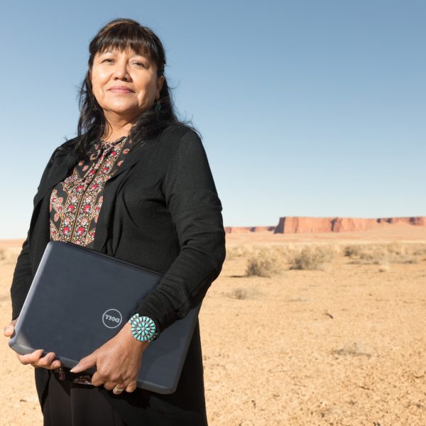 scilla Sanderson standing on Navajo Nation with red mesas far in the background.