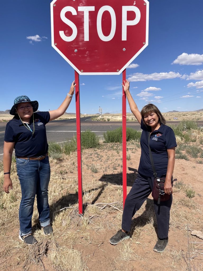 NAU student Melissa Howard and Professor Priscilla Sanderson next to a stop sign in Dilkon, Arizona on the Navajo Nation.