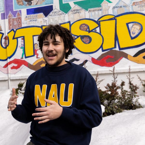 Undergraduate Ty Holliday talking with visitor in front of the Murdoch Community Center mural.