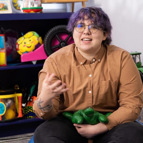 First-generation student, Charlie Dors talks with colleague in an early education classroom.