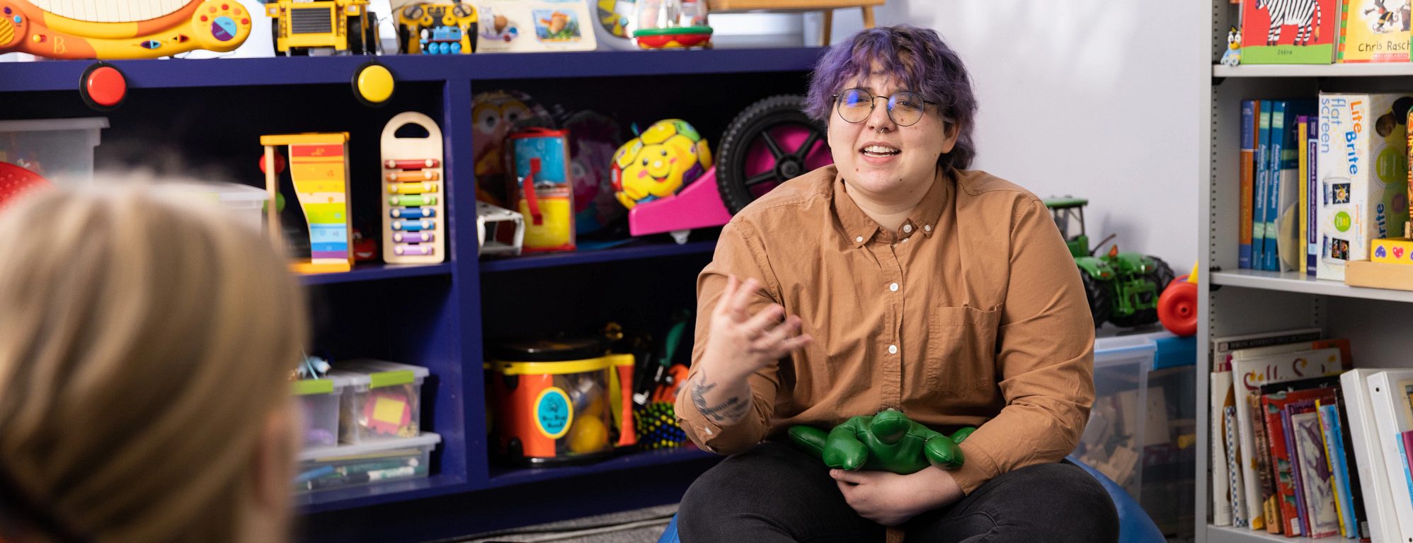 First-generation student, Charlie Dors talks with colleague in an early education classroom.