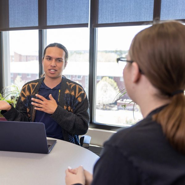 Undergraduate Research student Miguel Rosas talks with fellow student.