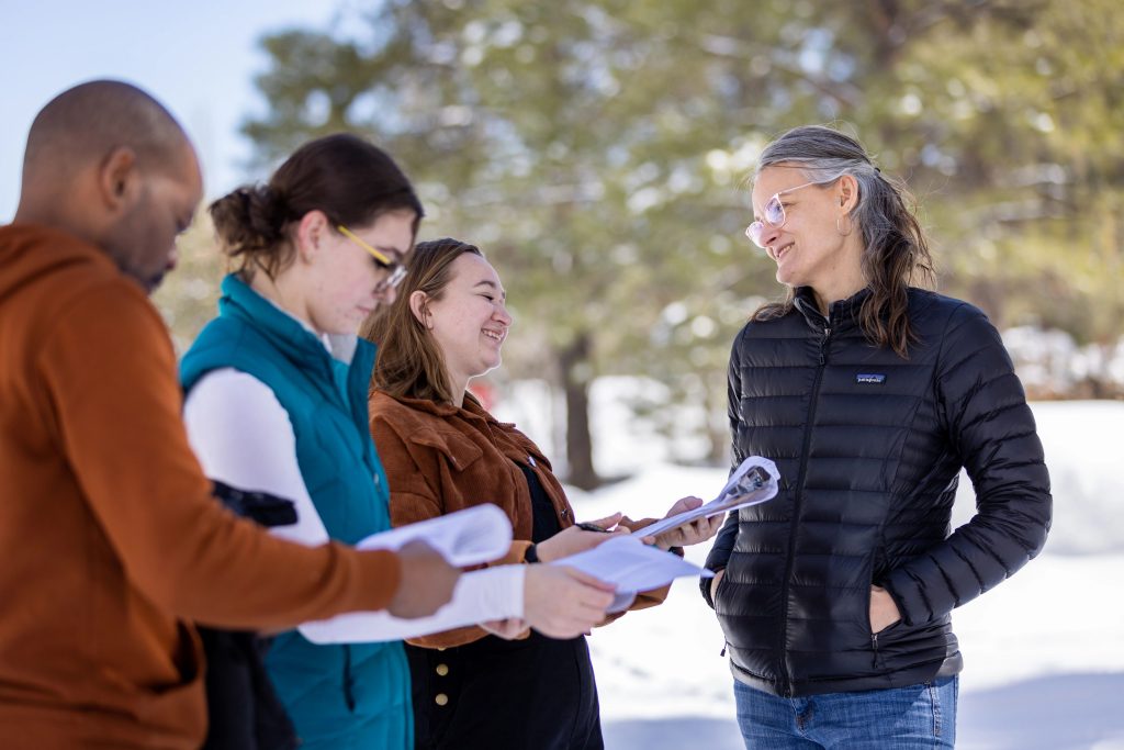 Associate Teaching Professor Nora Timmerman visits with three CUPI students who are conducting community surveys using clipboards.