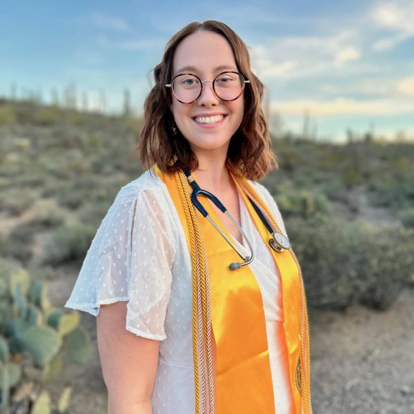 N A U graduate, RN Rachel Stearns, poses and smiles for a picture.