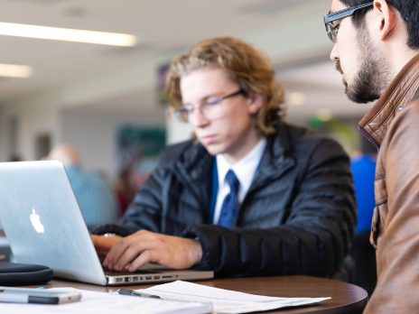 A student receiving help while working on their laptop.