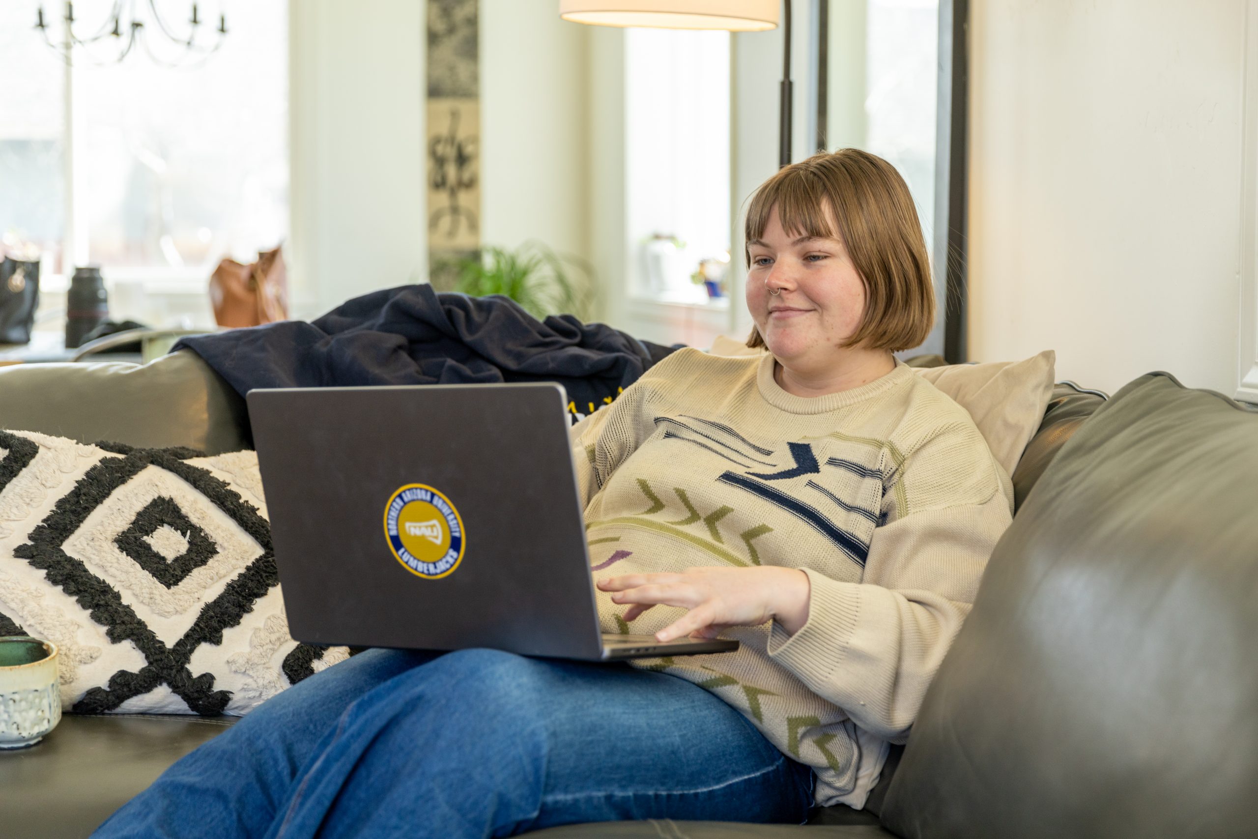 An N A U Online, first year student smiles while attending class from home.