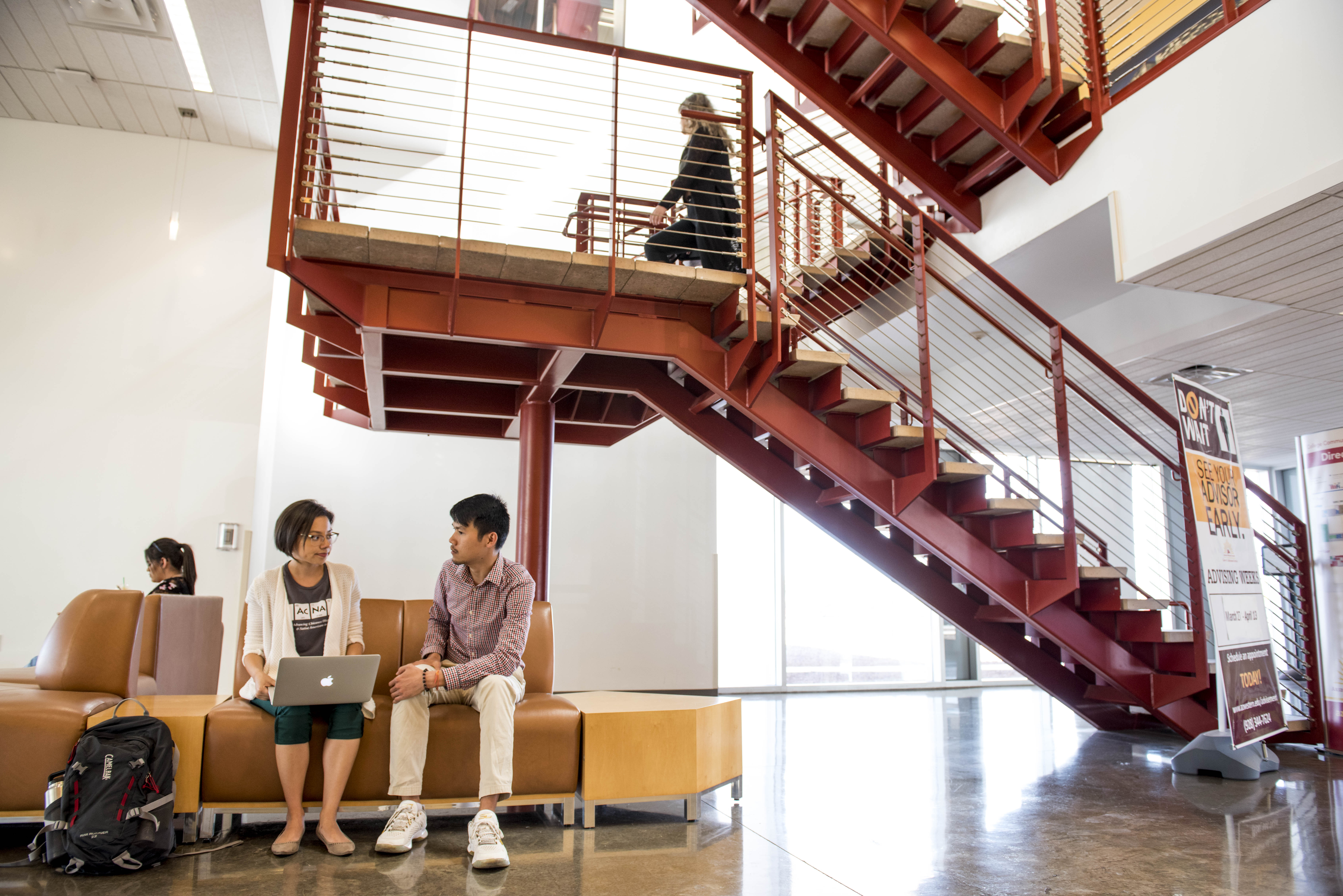 Students sitting on chairs under some stairs in the YUMA.