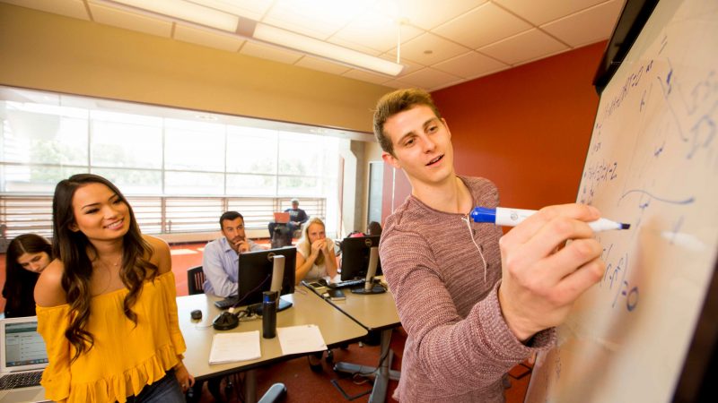 Student collaborating in an open lounge in the business building.