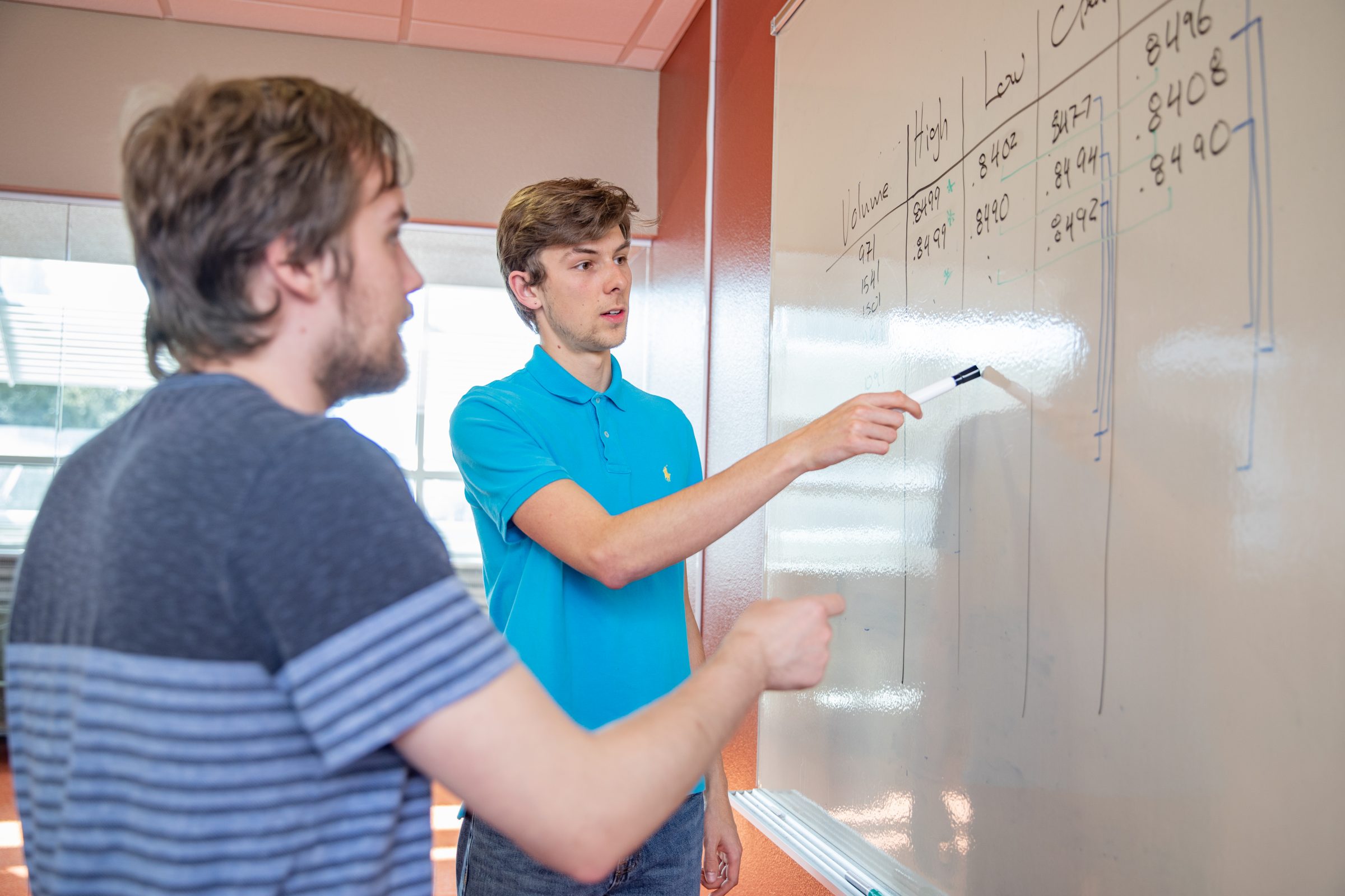 Students writing on a white board.