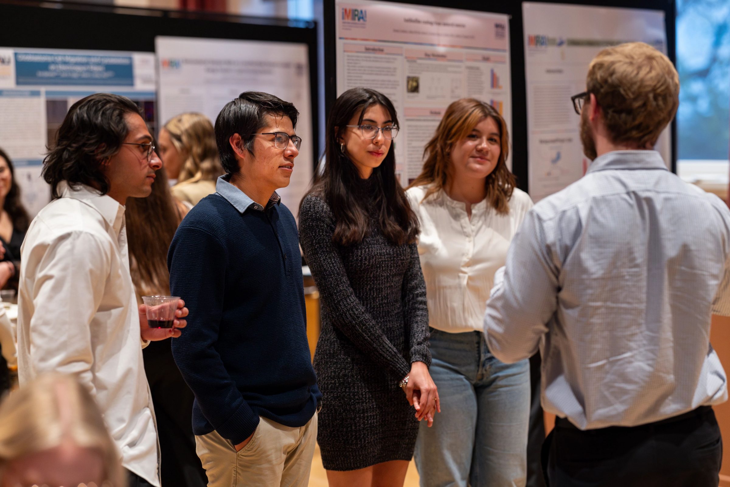 Group of four students listening to a research presentation from another student.