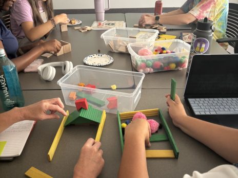 A table of magnetic blocks, where several adults are building random play scenarios.
