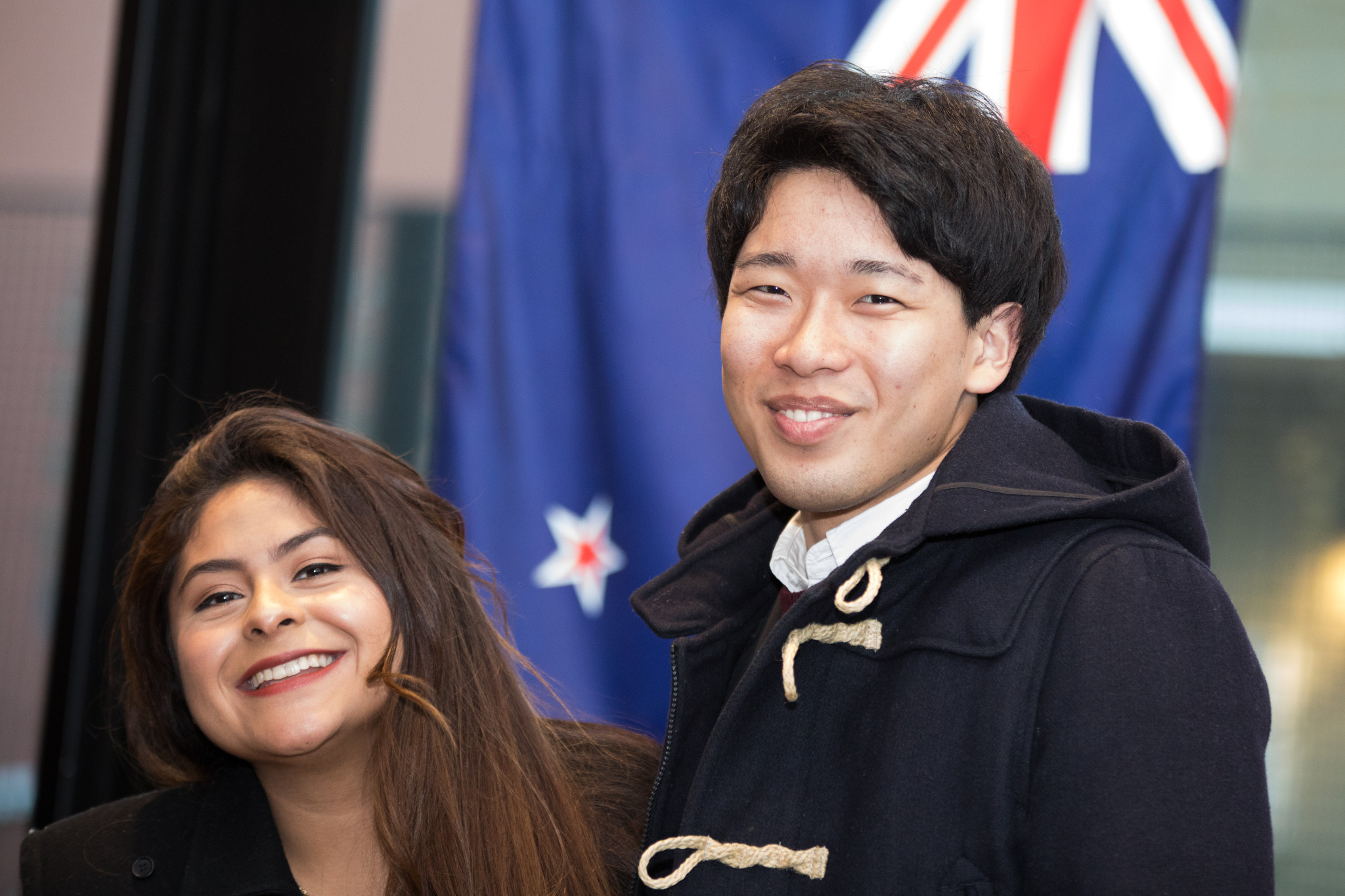 Students smiling in front of a flag.
