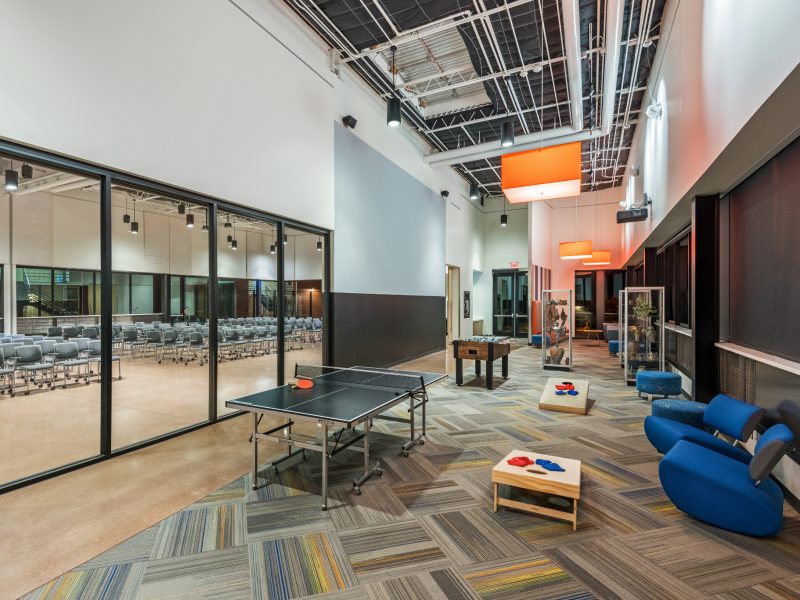 Hybrid area at the N A U International Pavilion featuring a conference room alongside a game room equipped with an audio-visual setup.