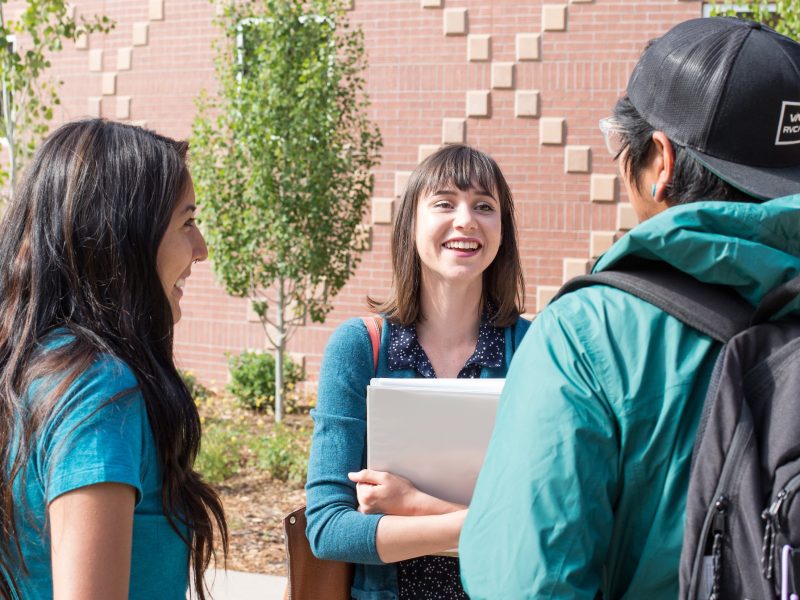 College of Arts and Letters alumni and friends talking and smiling outside.