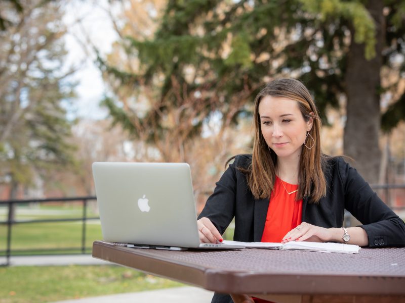 A student studying on their laptop at a table outside.