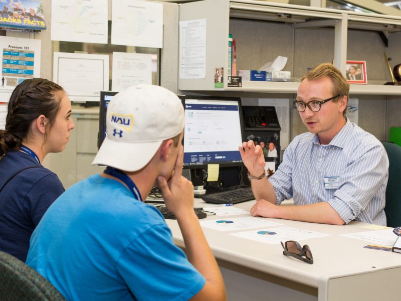 An advisor talking to students in his office.