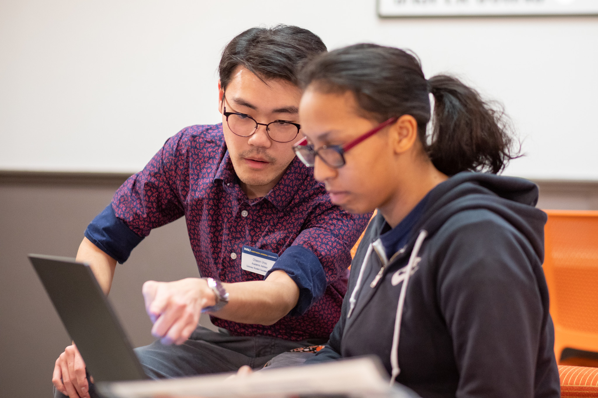 Advisor helps student on laptop.