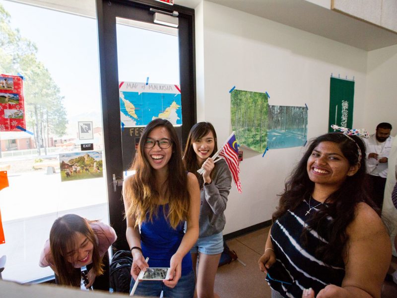 Students hold flags smiling and laughing.