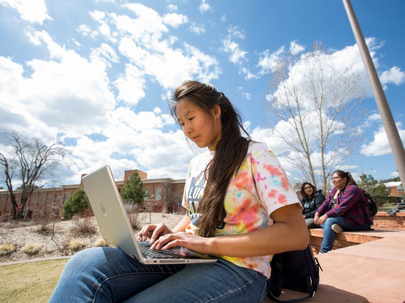 Student works on laptop outside.