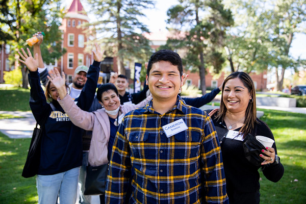Un grupo de estudiantes de NAU y alumnos parados en el North Quad con brazos levantados en celebración.