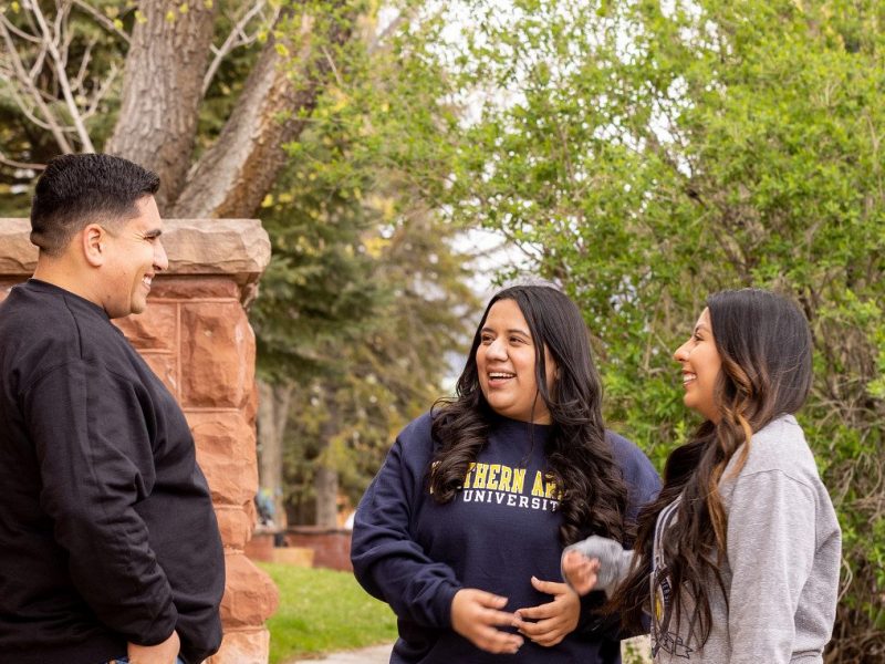 Tres estudiantes platican enfrente del edificio Old Main.