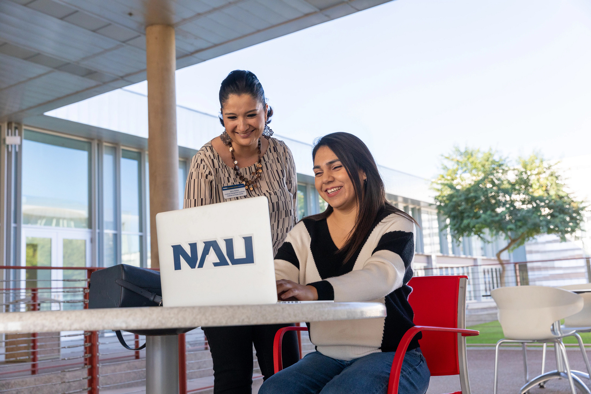 Un estudiante trabaja junto a un asesor académico enfrente de una computadora portátil.