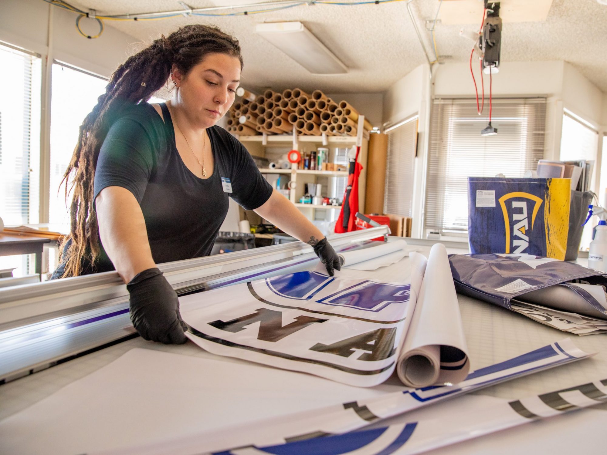 La coordinadora de servicios de impresi&oacute;n de NAU, Sara LaRosa, crea una pancarta promocional en la imprenta del campus.